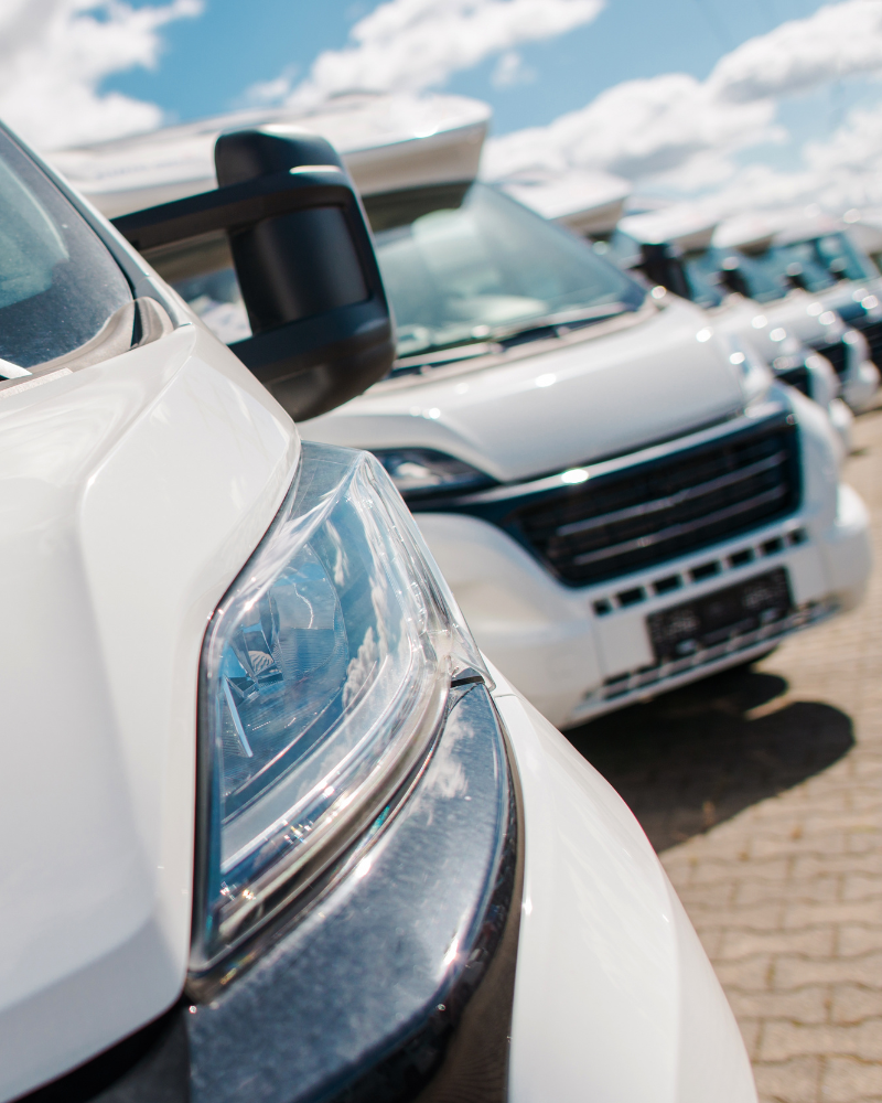 A close up view of a headlight of a RV and more RV's at the back parked.