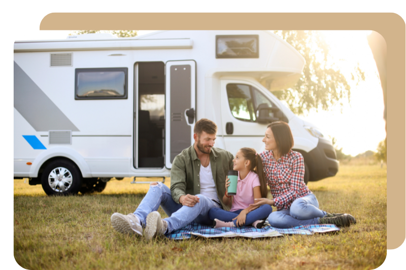 A family happily seating outside with RV parked behind them.